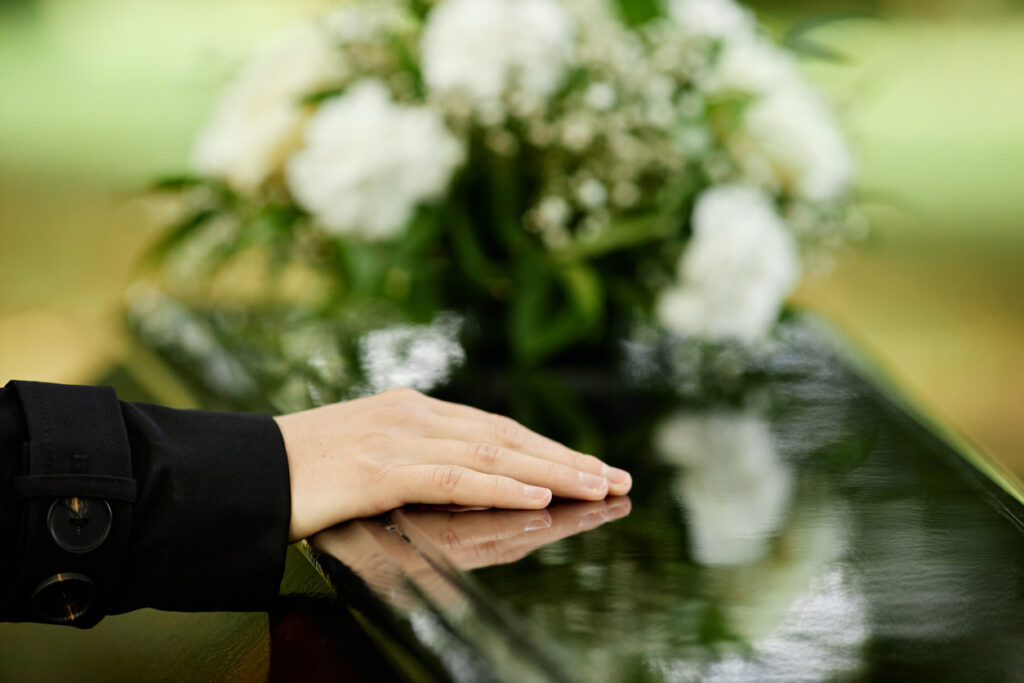 close up of female hand on coffin. Wrongful Death Lawyer in Pismo Beach, Ca